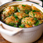 Minted lamb stew with dumplings, swede and carrots in a cooking pot.