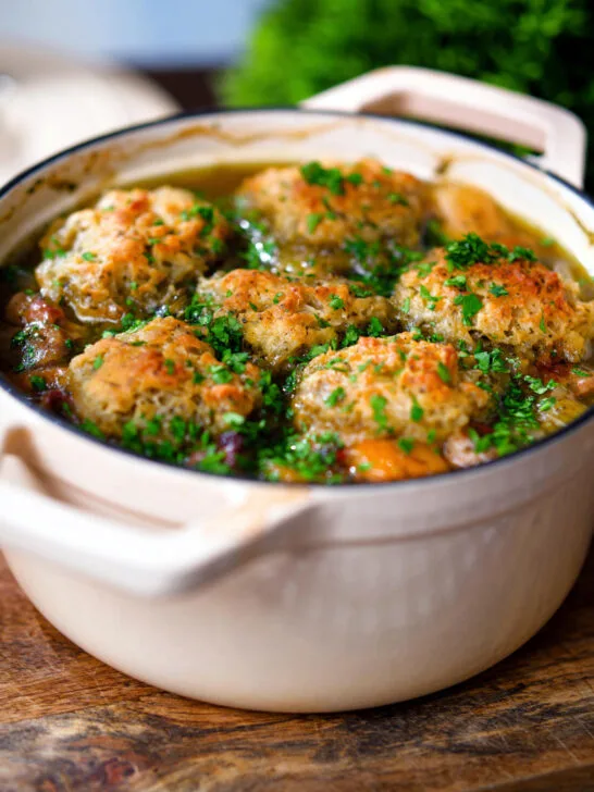 Minted lamb stew with dumplings, swede and carrots in a cooking pot.