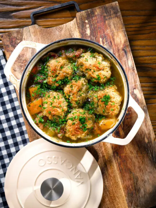 Overhead minted lamb stew with dumplings, swede and carrots in a cooking pot.