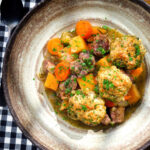 Overhead minted lamb stew with dumplings, swede and carrots.