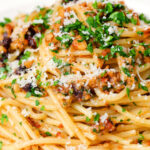 Close-up pasta foriana with walnuts, pine nuts and raisins garnished with parsley.