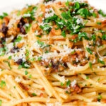 Close-up pasta foriana with walnuts, pine nuts and raisins garnished with parsley.
