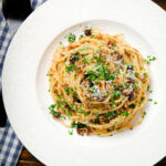 Overhead pasta foriana with walnuts, pine nuts and raisins garnished with parsley.