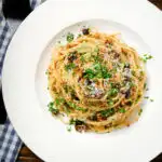 Overhead pasta foriana with walnuts, pine nuts and raisins garnished with parsley.