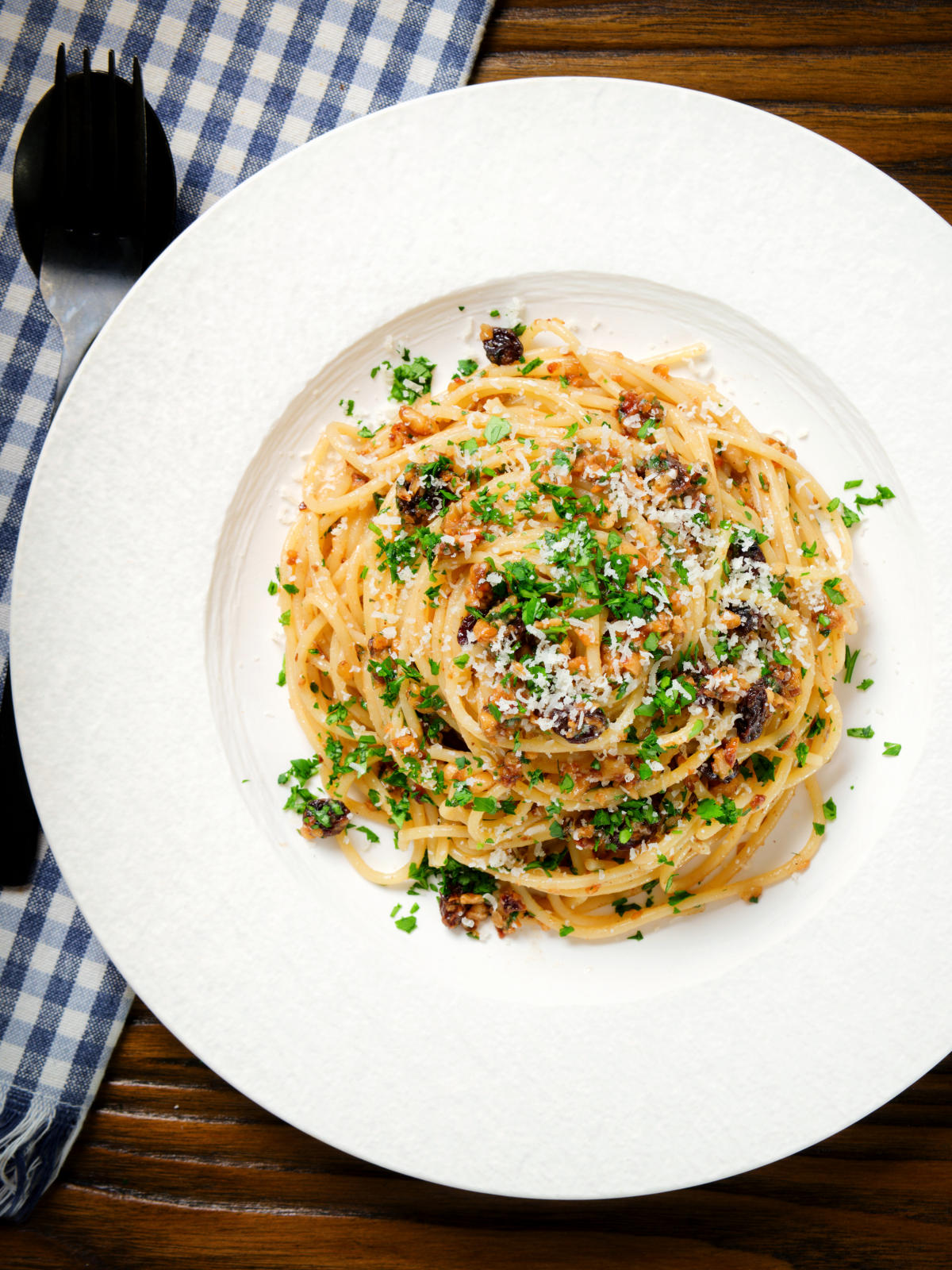 Overhead pasta foriana with walnuts, pine nuts and raisins garnished with parsley.