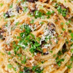 Close-up overhead pasta foriana with walnuts, pine nuts and raisins garnished with parsley.