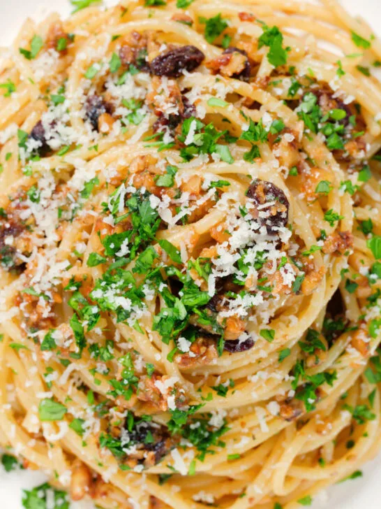 Close-up overhead pasta foriana with walnuts, pine nuts and raisins garnished with parsley.