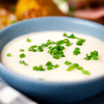 Overhead close-up French soubise (white onion sauce) with snipped chives.