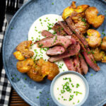 Overhead French soubise (onion sauce) with bavette steak and crushed roasted potatoes.