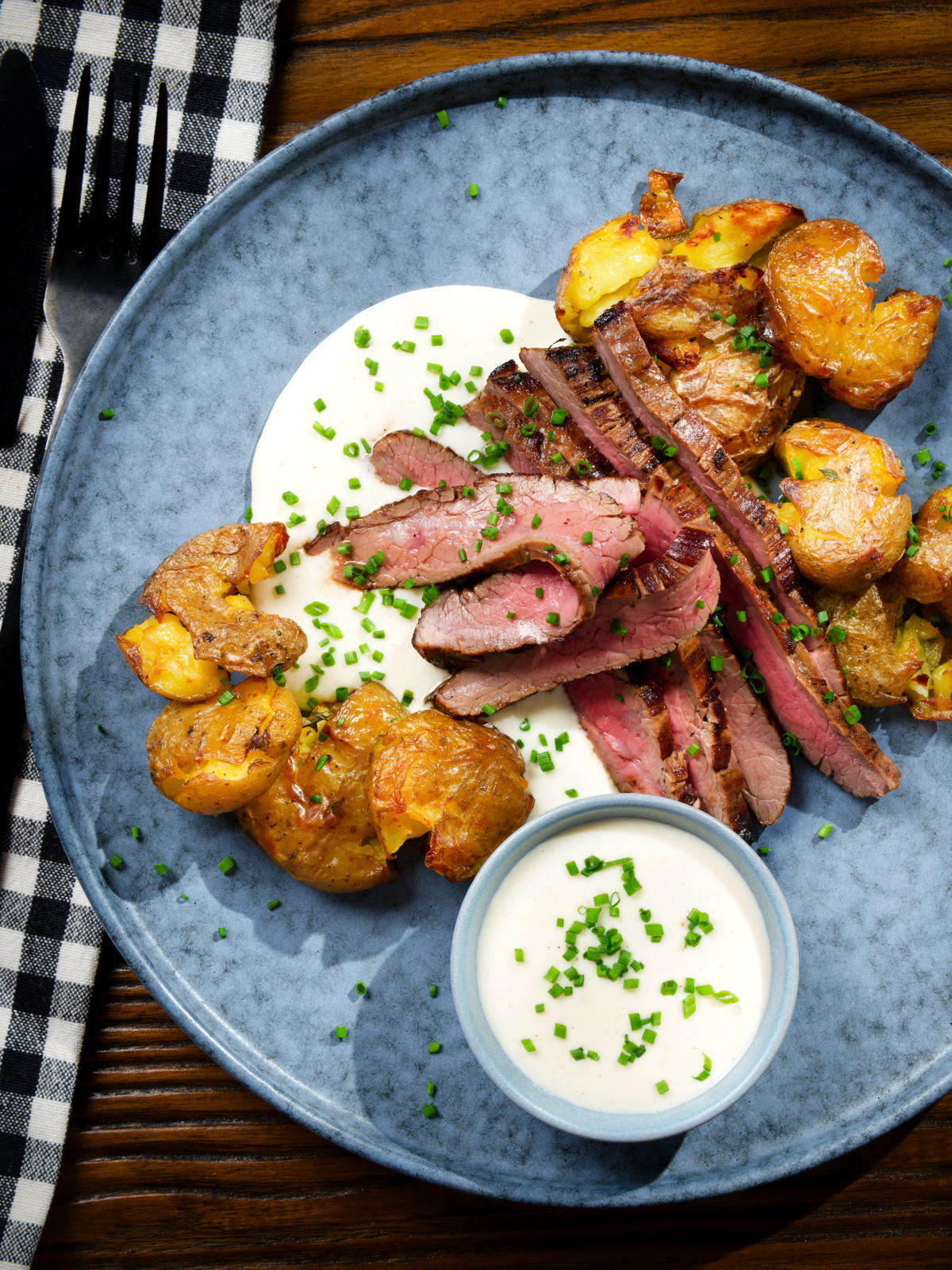 Overhead French soubise (onion sauce) with bavette steak and crushed roasted potatoes.