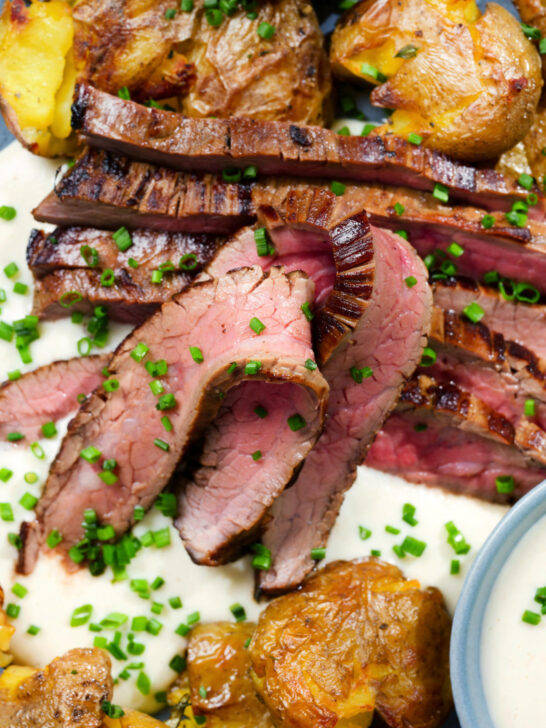 Overhead close-up marinated steak bavette (Flank Steak) served with soubise and crushed potatoes.