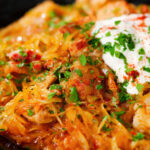 Close-up Hungarian sz&eacute;kelyk&aacute;poszta: pork belly and sauerkraut stew served with sour cream.