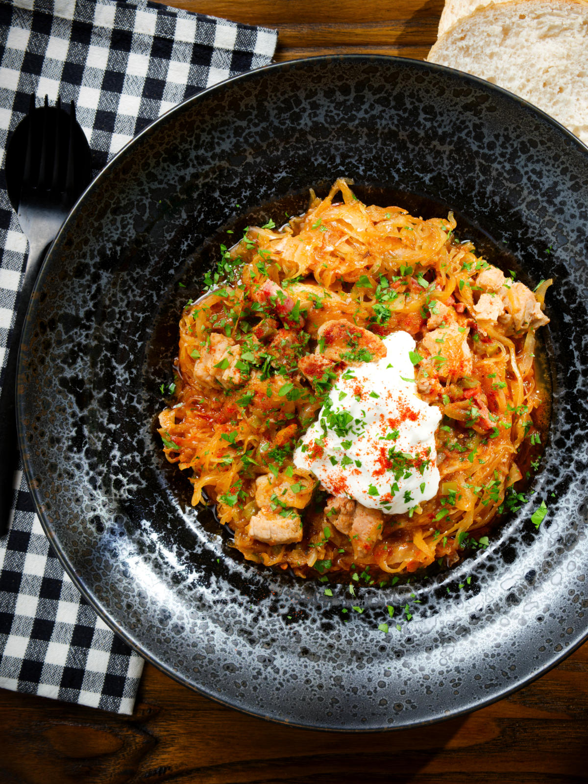 Overhead Hungarian székelykáposzta: pork belly and sauerkraut stew served with sour cream and bread.