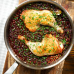 Overhead close-up chicken leg and pearl barley stew in its cooking pan.