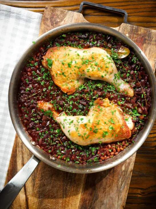 Overhead close-up chicken leg and pearl barley stew in its cooking pan.