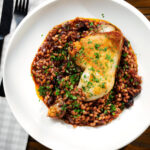 Overhead chicken leg and pearl barley stew with red wine and prunes.