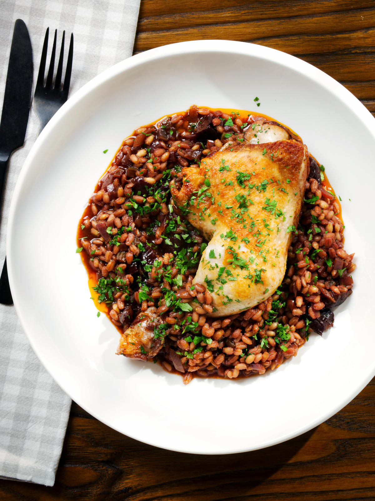 Overhead chicken leg and pearl barley stew with red wine and prunes.