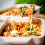 Baked gnocchi alla sorrentina with a tomato and cheese sauce being picked up with a spoon.