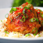 Close-up baked Thai red curry chicken thighs served with egg fried rice.