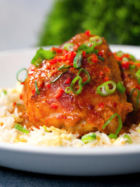 Close-up baked Thai red curry chicken thighs served with egg fried rice.