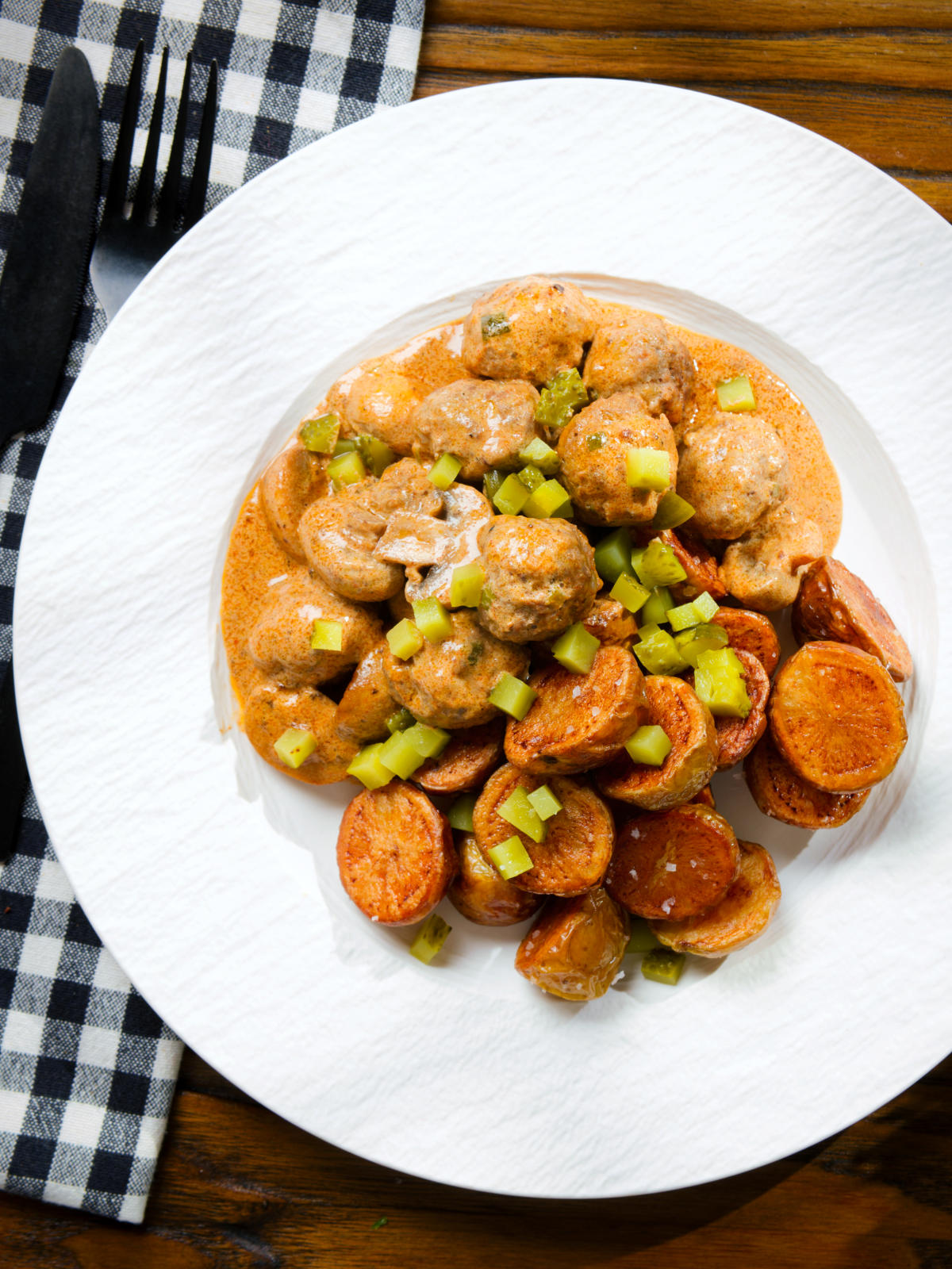 Overhead creamy beef meatball stroganoff served with crispy fried potatoes.