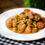Beef meatball stroganoff with fried potatoes and chopped gherkins.