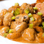Close-up creamy beef meatball stroganoff served with crispy fried potatoes.