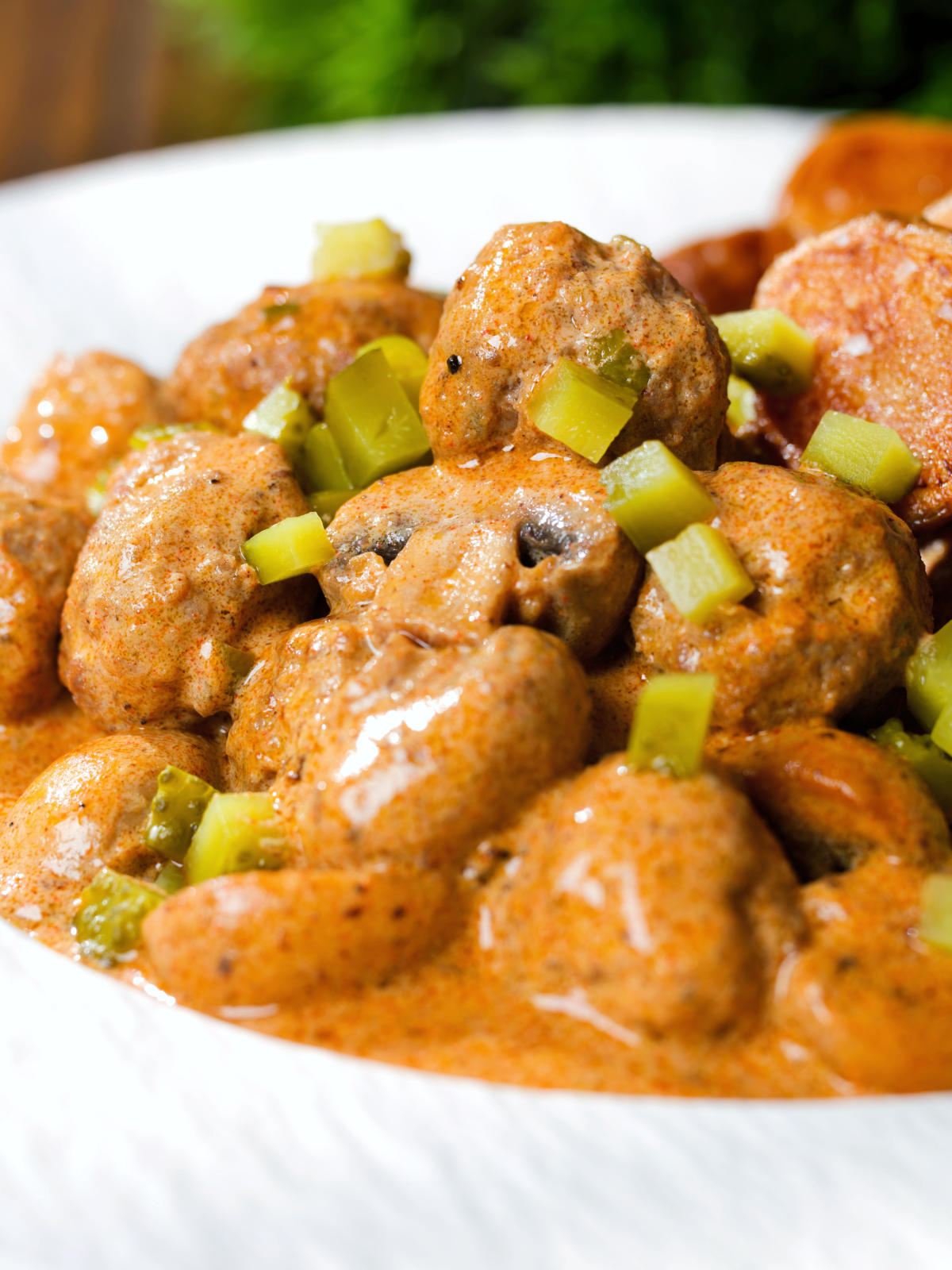 Close-up creamy beef meatball stroganoff served with crispy fried potatoes.