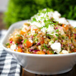 Close-up warm freekeh salad with feta cheese, peppers, tomatoes and parsley.