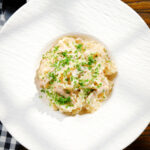 Overhead honey and mustard chicken pasta (malfadine) with chopped parsley.
