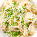 Overhead close-up honey and mustard chicken pasta (malfadine) with chopped parsley.
