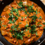 Overhead close-up Kashmiri-style chicken curry served in a kadai with coriander.