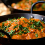Close-up Kashmiri-style chicken curry served in a kadai with coriander.