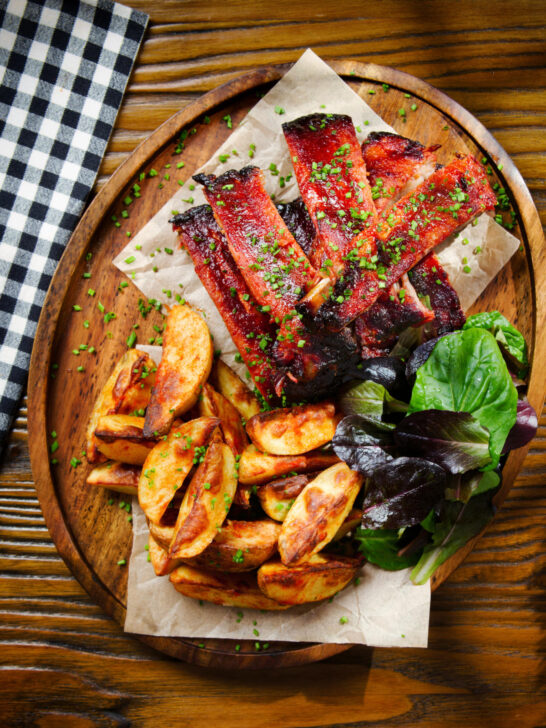 Overhead Korean gochujang glazed pork ribs served with potato wedges.