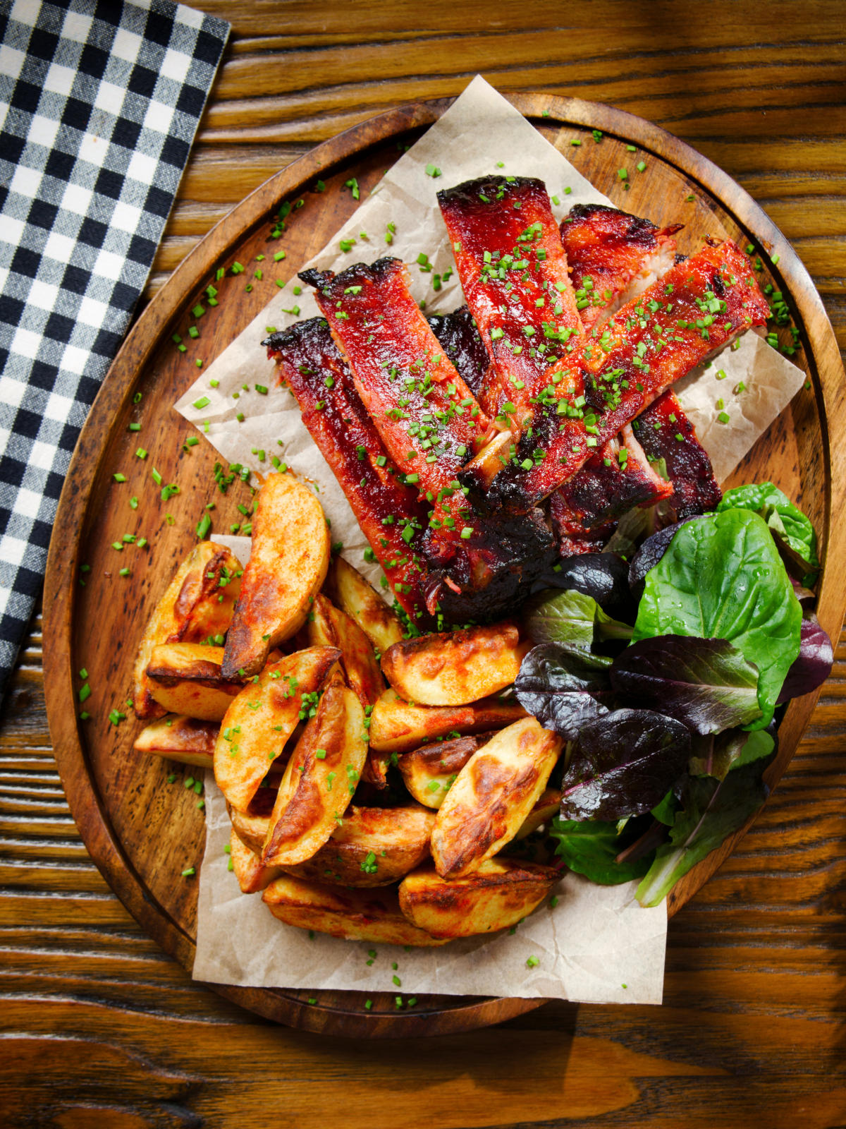 Overhead Korean gochujang glazed pork ribs served with potato wedges.