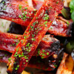 Overhead close-up Korean gochujang glazed pork ribs served with potato wedges.