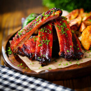 Korean gochujang pork ribs served with snipped chives and potato wedges.