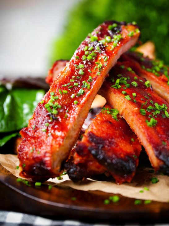 Close-up Korean gochujang glazed pork ribs served with snipped chives.