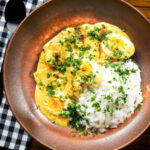 Overhead kuku paka: African chicken curry with boiled eggs served with white rice.