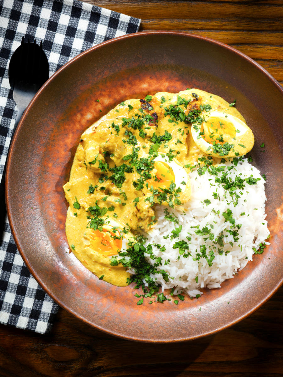Overhead kuku paka: African chicken curry with boiled eggs served with white rice.