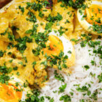 Overhead close-up kuku paka: African chicken curry with boiled eggs served with white rice.
