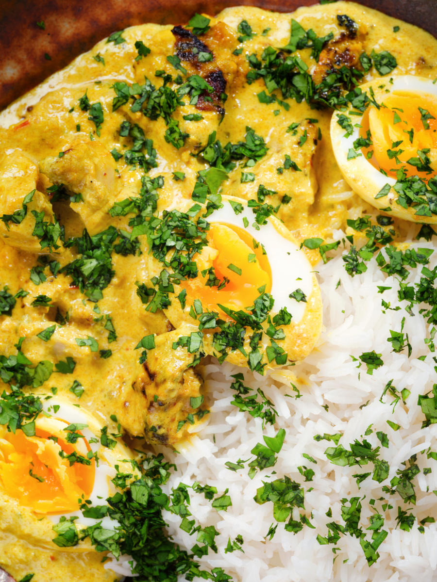 Overhead close-up kuku paka: African chicken curry with boiled eggs served with white rice.