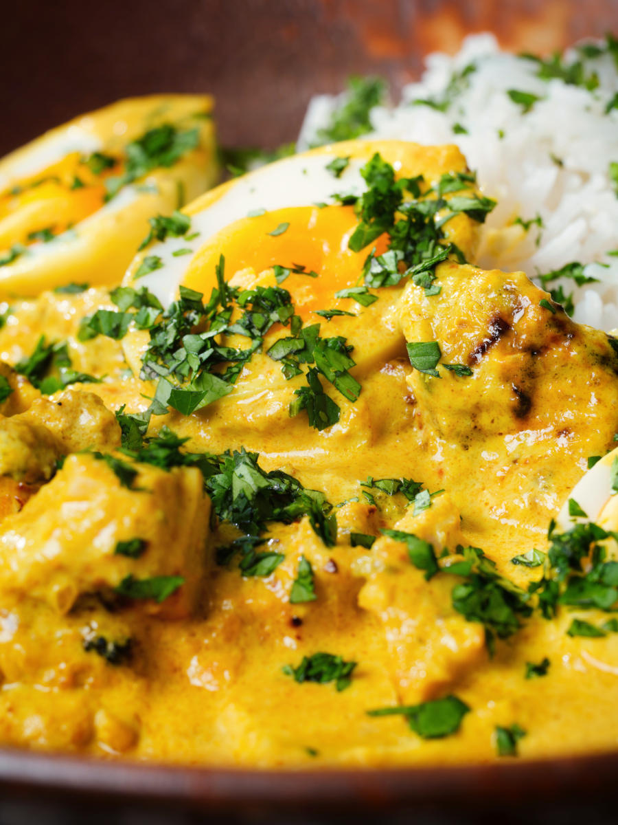 Close-up kuku paka: African chicken curry with boiled eggs served with white rice.