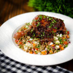Pomegranate glazed duck leg baked with onions, served with a feta freekeh salad.