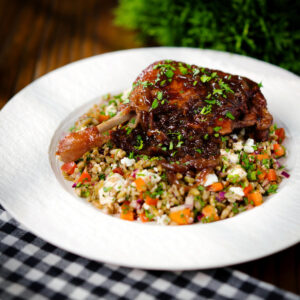 Pomegranate glazed duck leg baked with onions, served with a feta freekeh salad.