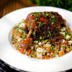 Baked pomegranate molasses duck leg with onions, served with a feta freekeh salad.