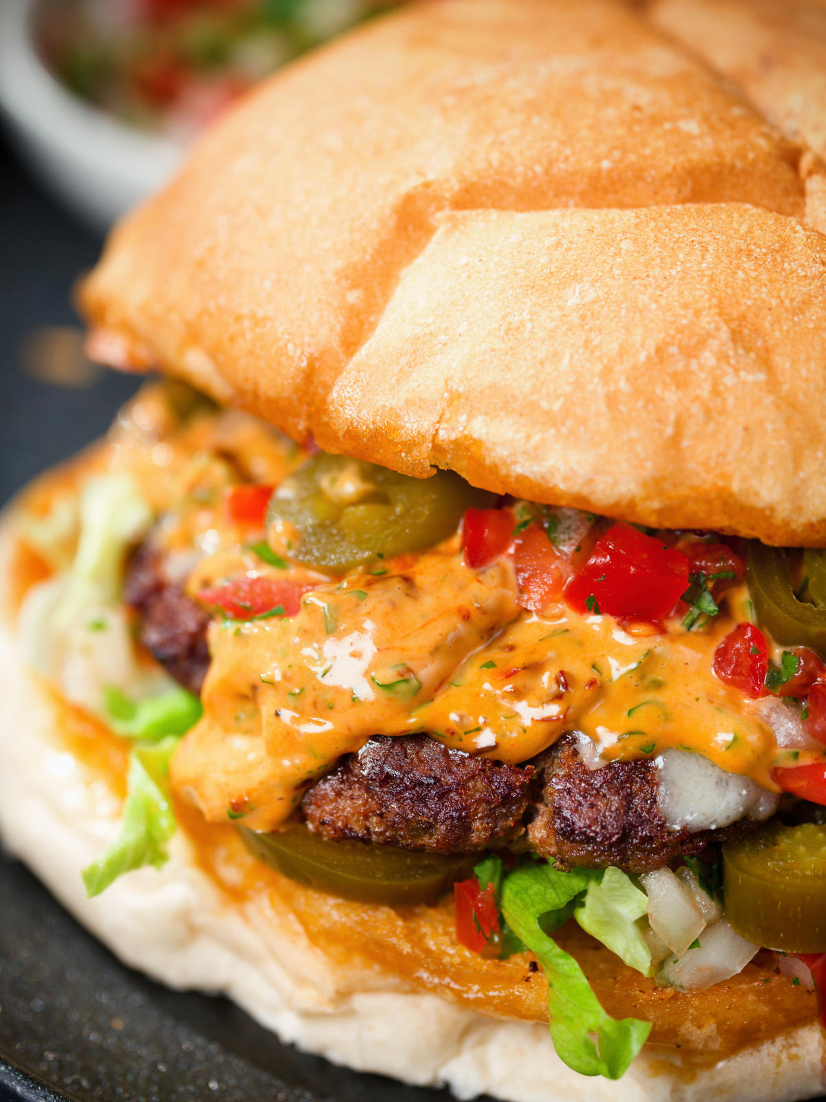 Close-up Mexican beef burger with salsa fresca, chipotle mayonnaise.