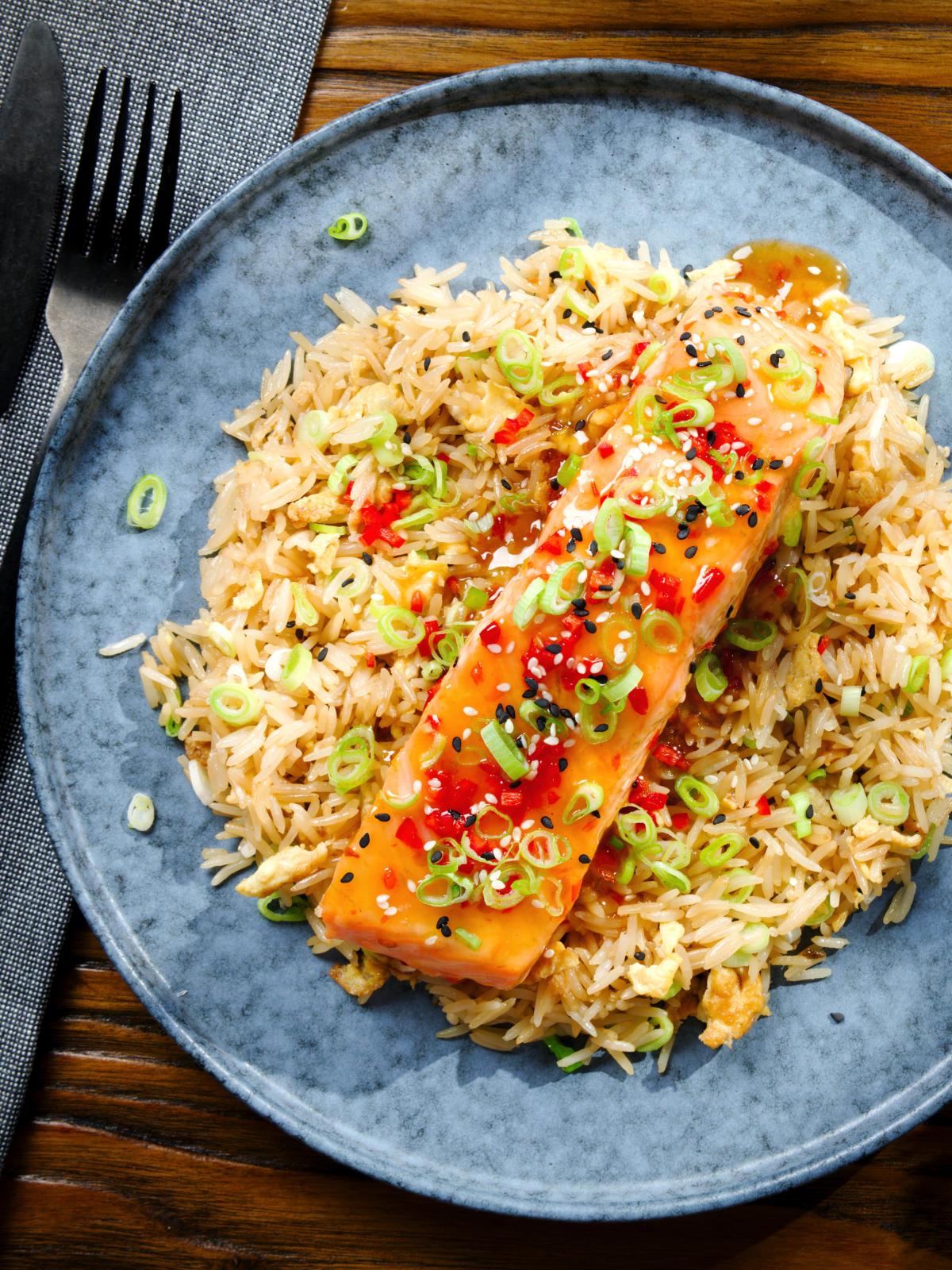 Overhead sweet chilli sauce baked salmon with egg fried rice, fresh chilli and spring onions.