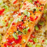 Overhead close-up sweet chilli sauce baked salmon with egg fried rice, fresh chilli and spring onions.
