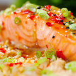 Close-up sweet chilli sauce baked salmon with egg fried rice, fresh chilli and spring onions.